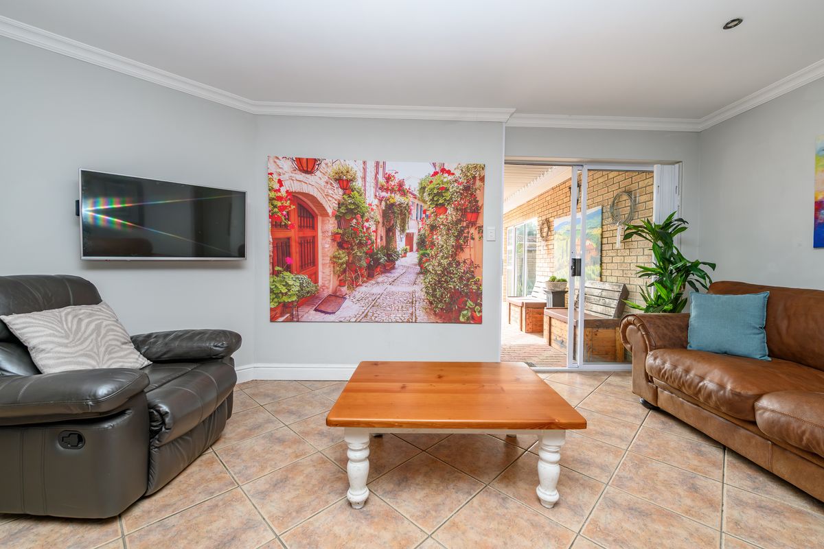 A living room featuring tiled flooring, coved ceilings, and a sliding glass door providing access to an outdoor patio area.