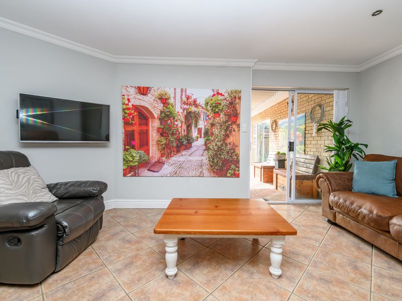 A living room featuring tiled flooring, coved ceilings, and a sliding glass door providing access to an outdoor patio area.