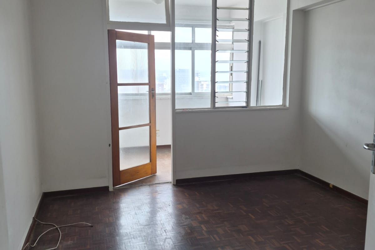 An empty bedroom featuring original parquet flooring, a timber-framed door, and access to an adjoining balcony area.