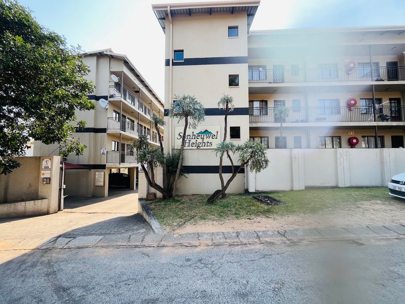 Front exterior view of Sonheuwel Heights apartment complex, featuring multi-story residential units with balconies and a paved driveway entrance.