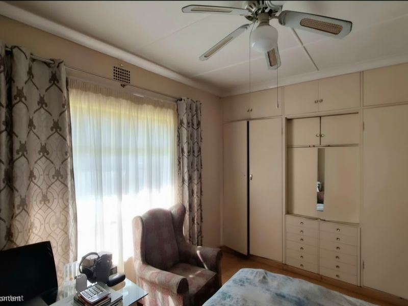 A bedroom featuring extensive built-in cabinetry with integrated drawers and a ceiling fan, offering functional storage space.