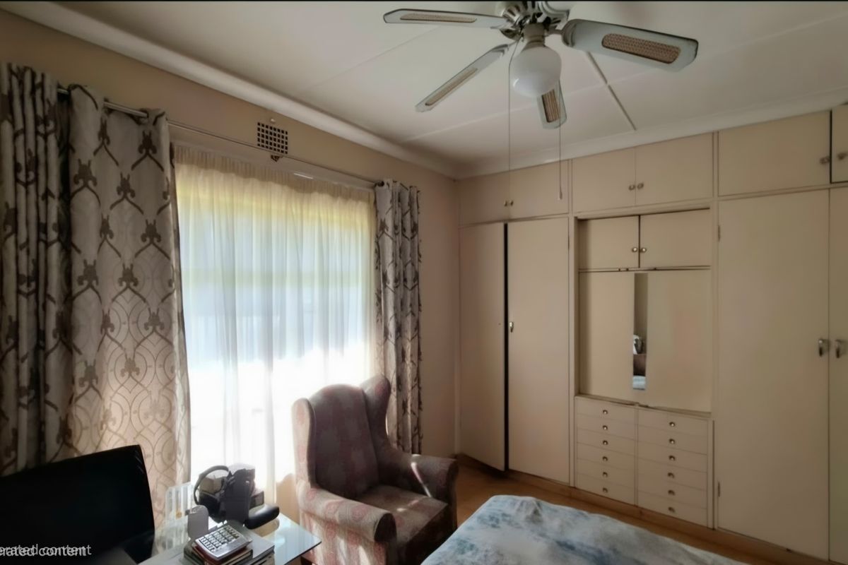 A bedroom featuring extensive built-in cabinetry with integrated drawers and a ceiling fan, offering functional storage space.
