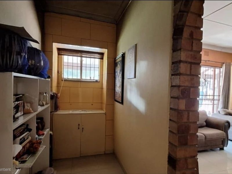 A hallway featuring a brick archway leading to the living area, with built-in cabinetry and tiled flooring.
