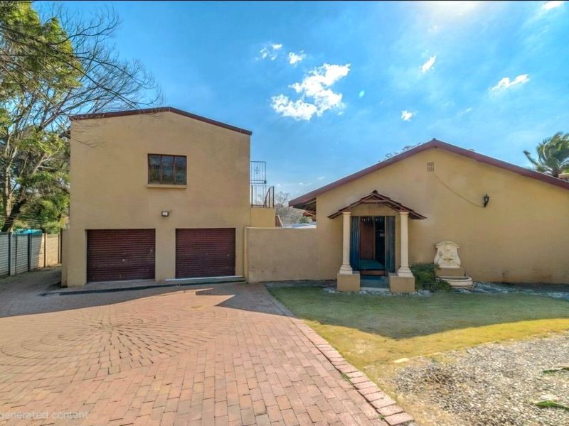 Front elevation of the property featuring a double garage, paved driveway, and a covered entrance porch with a decorative wall fountain.
