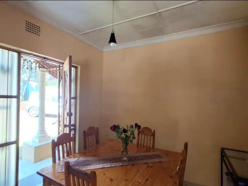 A dining room featuring a glass panel door leading to the exterior, with a tiled ceiling and neutral wall finishes.