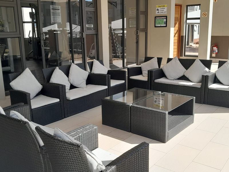 A covered outdoor patio area featuring tiled flooring and access to the adjacent indoor facility through large sliding glass doors.