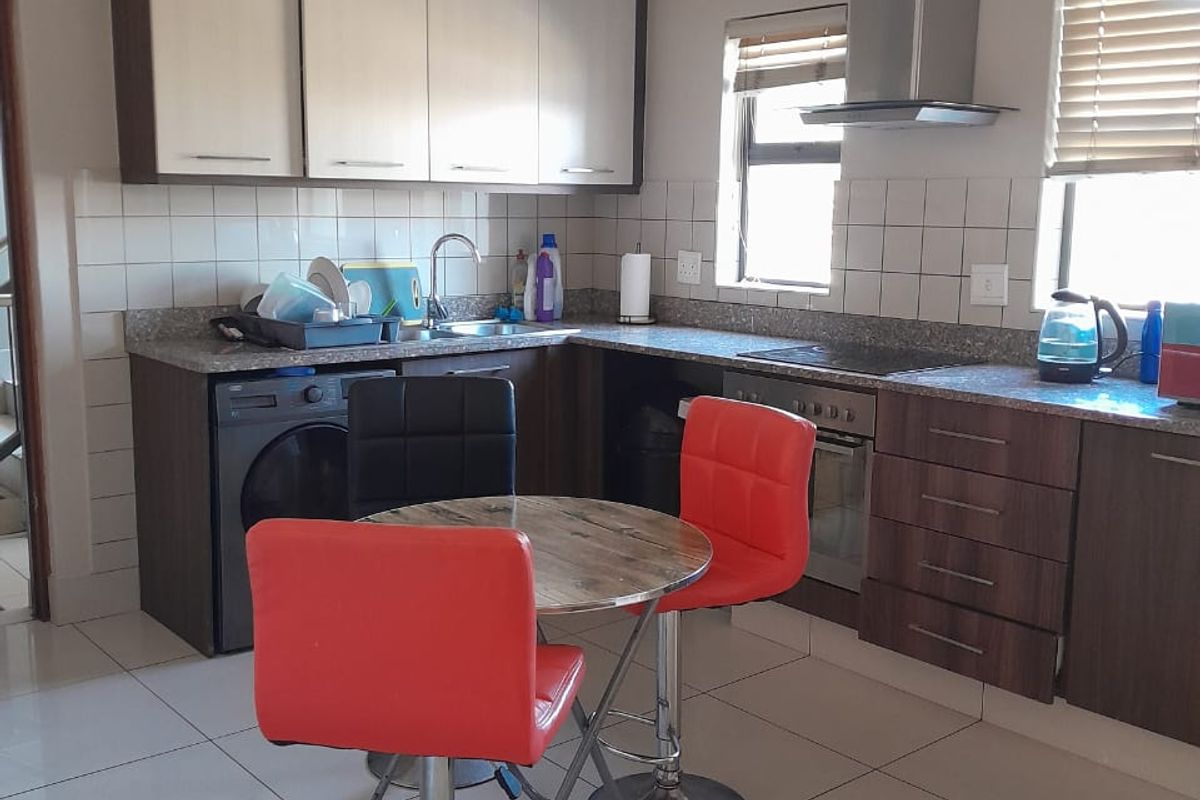 Functional kitchen featuring two-tone cabinetry, tiled backsplash, integrated oven with extractor fan, and tiled flooring, providing a practical workspace.