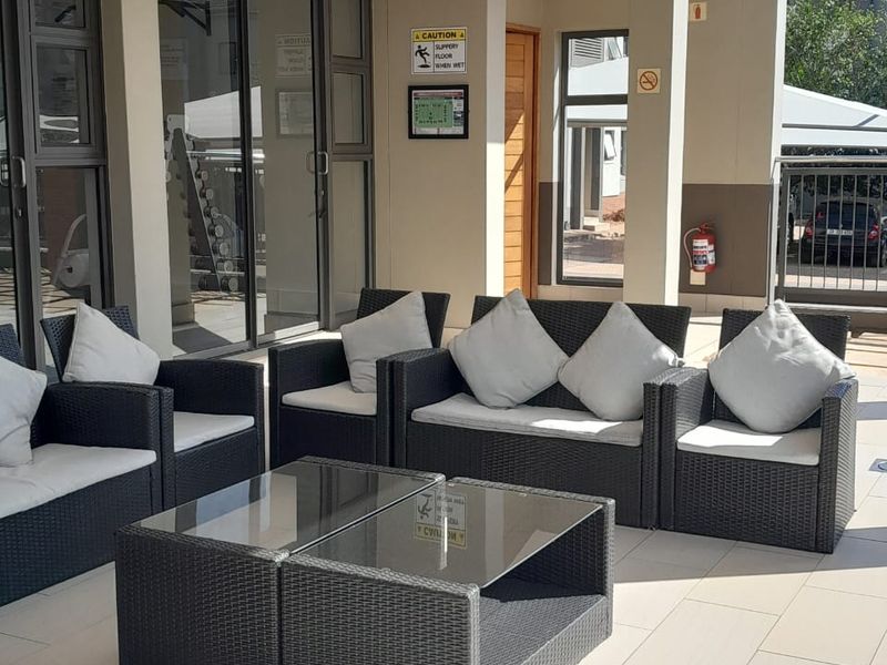 A covered outdoor patio area featuring tiled flooring, recessed lighting, and access to the interior through large sliding glass doors.