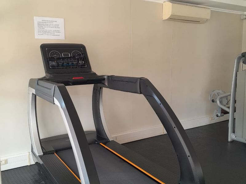A functional gym space featuring rubber flooring, wall-mounted air conditioning, and overhead fluorescent lighting.