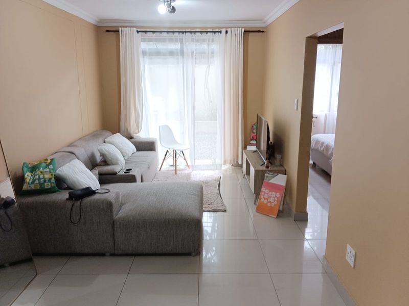A living room featuring tiled flooring, coved ceilings, and a sliding glass door providing access to the exterior.
