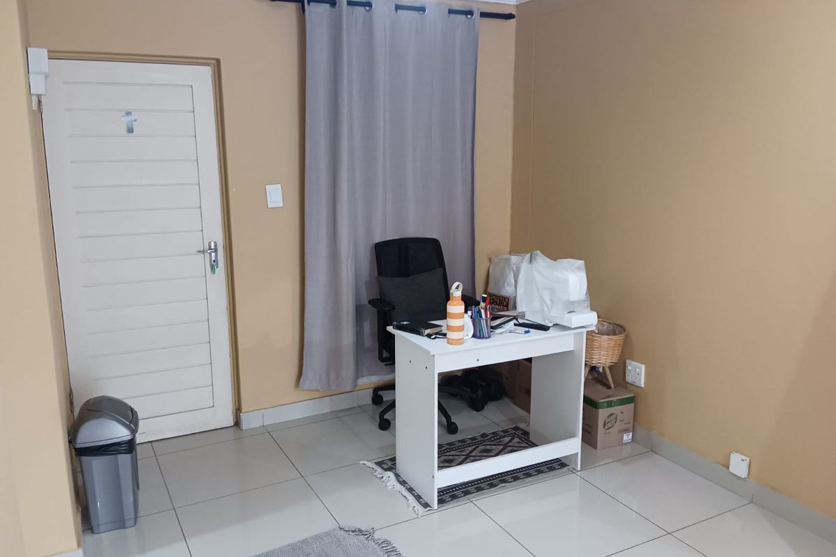 A functional bedroom space featuring tiled flooring, neutral wall paint, and a curtain rod, suitable for use as a bedroom or home office.