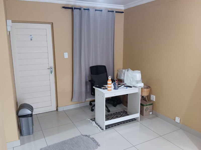 A functional bedroom space featuring tiled flooring, neutral wall paint, and a curtain rod, suitable for use as a bedroom or home office.