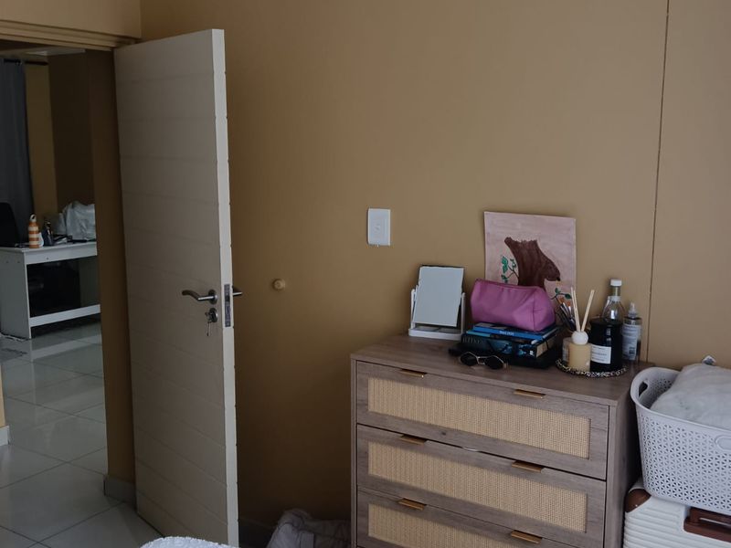 A bedroom featuring neutral-toned walls, crown molding, and a standard internal door leading to an adjacent tiled space.