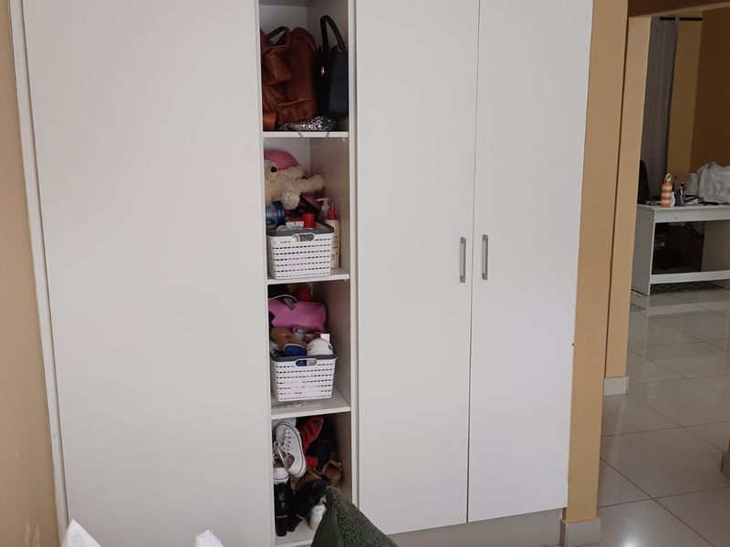 Bedroom featuring a large white built-in wardrobe with integrated shelving and tiled flooring.