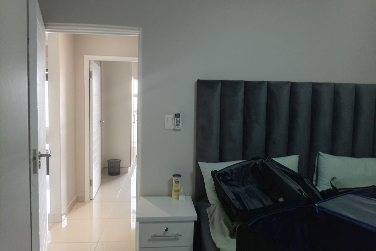 A bedroom featuring tiled flooring and access to an adjoining hallway, showing a neutral color palette and standard interior finishes.