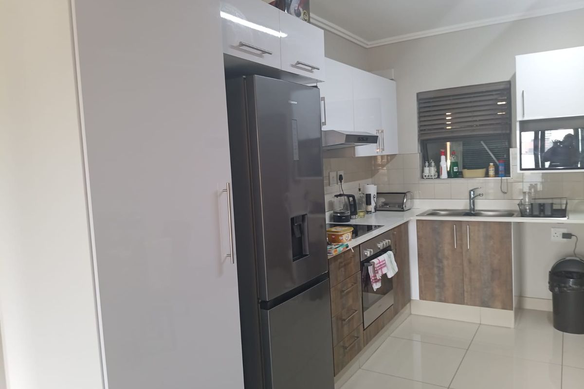 Modern kitchen featuring two-tone cabinetry, stainless steel sink, built-in oven, hob, extractor fan, and tiled flooring.