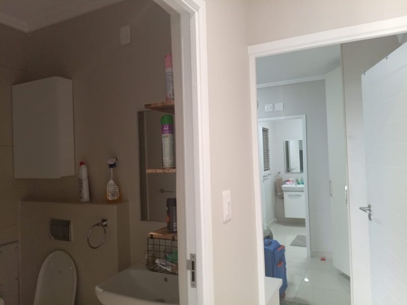 A view through a doorway into a bathroom featuring a wall-mounted toilet with a concealed cistern and a vanity basin.