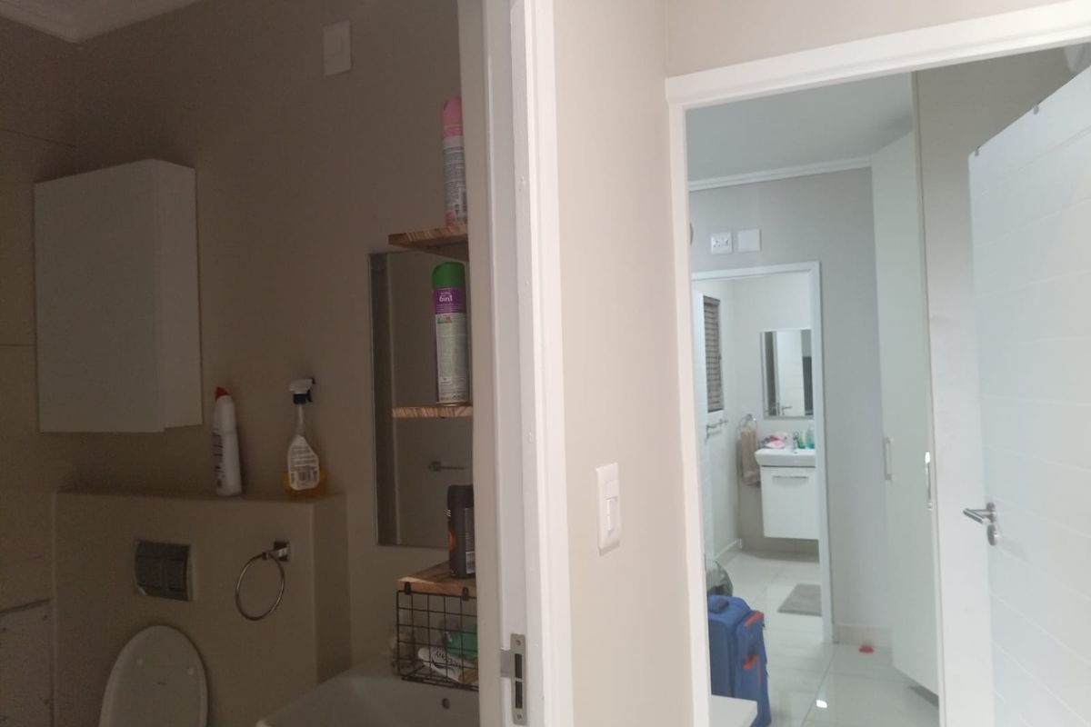 A view through a doorway into a bathroom featuring a wall-mounted toilet with a concealed cistern and a vanity basin.