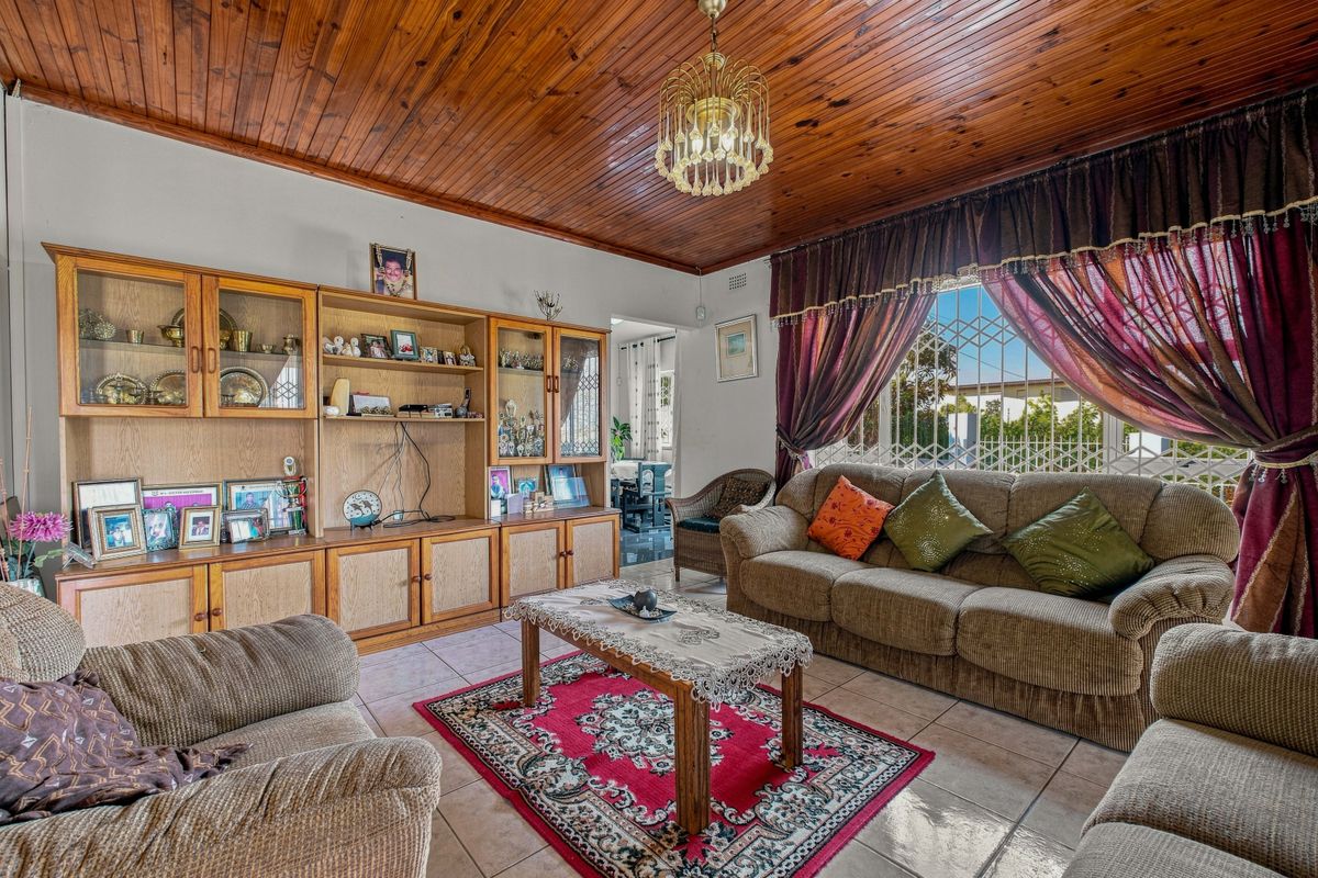 A traditional living room featuring a warm timber tongue and groove ceiling, tiled flooring, and built-in cabinetry, offering a classic and functional living space.