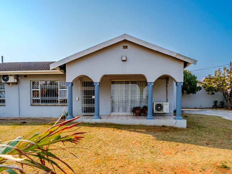 Rear exterior view of the house featuring a covered patio with decorative columns, security gates, and sliding glass doors.