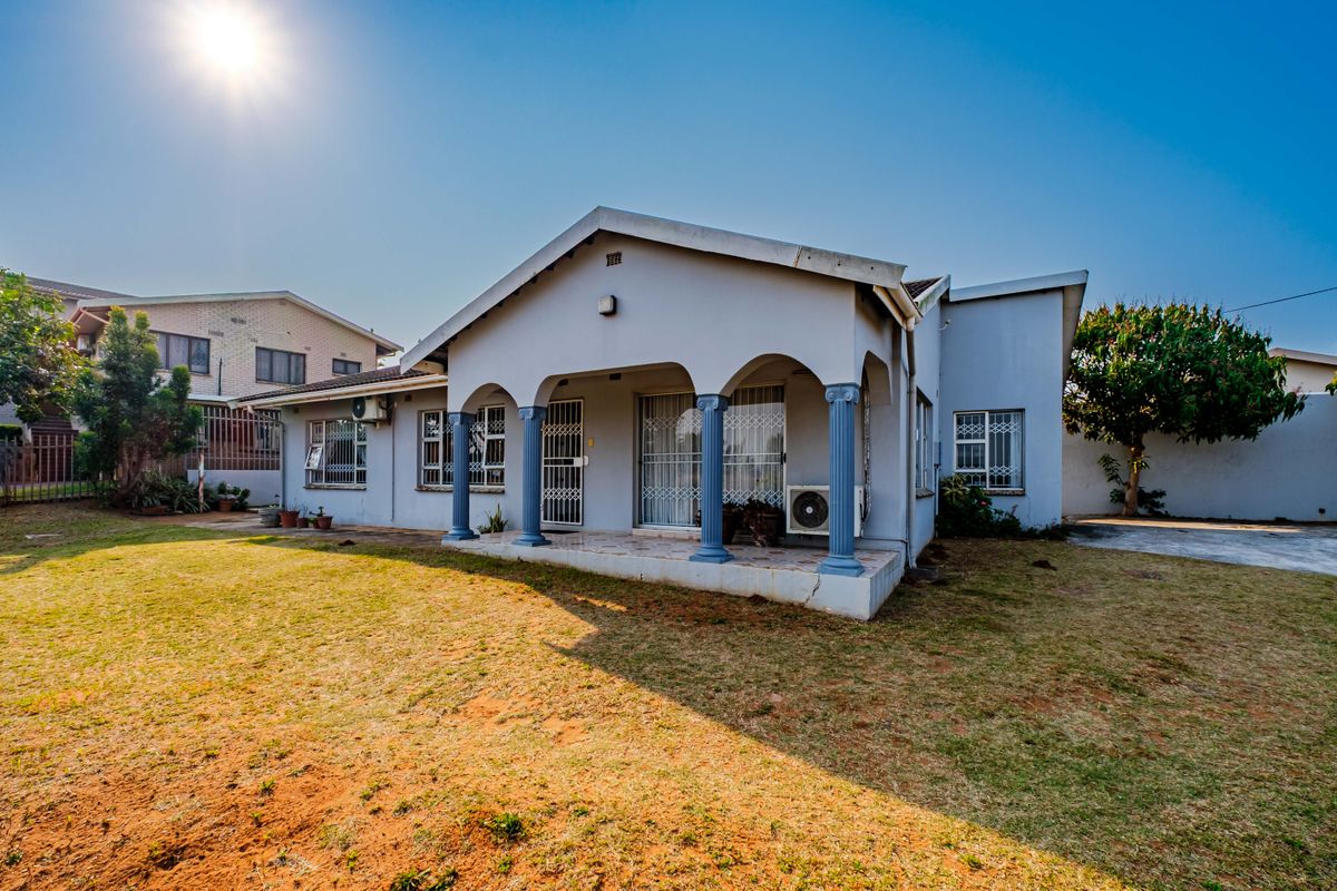 Rear view of the house featuring a covered patio with decorative columns, security gates, and an established garden area.