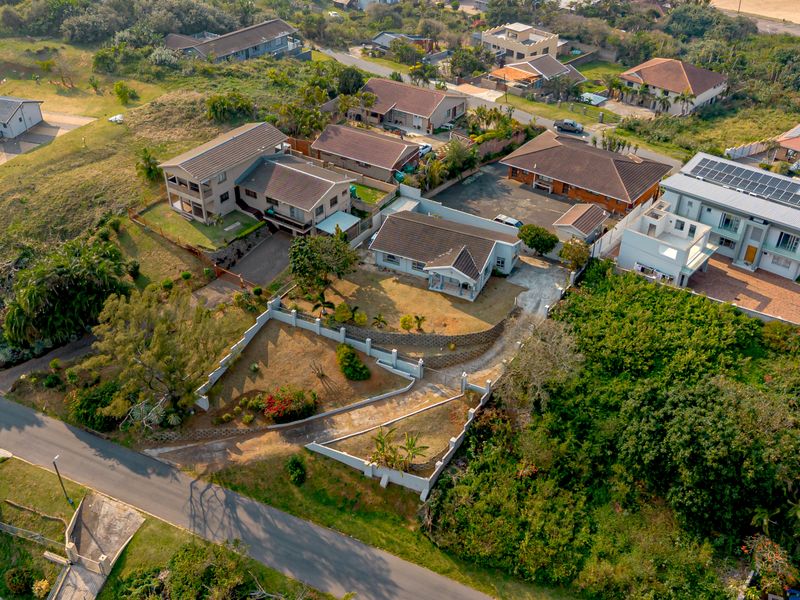 Aerial view of the residential property showing the main dwelling, driveway, surrounding garden, and neighborhood context.