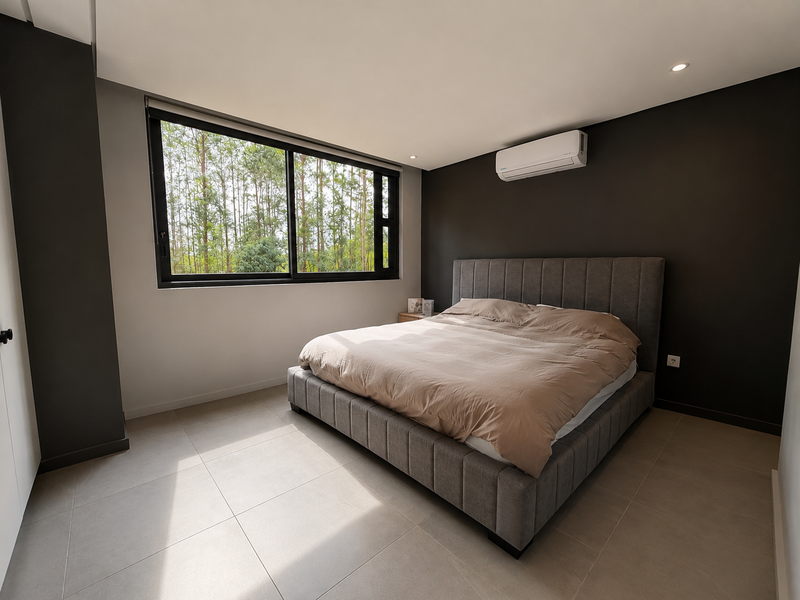 Modern bedroom featuring neutral tiled flooring, dark accent walls, a large window with natural light, and a wall-mounted split-system air conditioner.