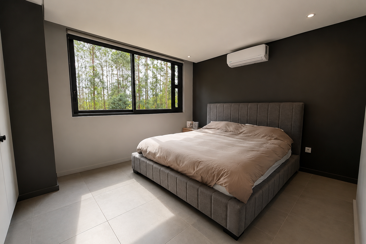 Modern bedroom featuring neutral tiled flooring, dark accent walls, a large window with natural light, and a wall-mounted split-system air conditioner.