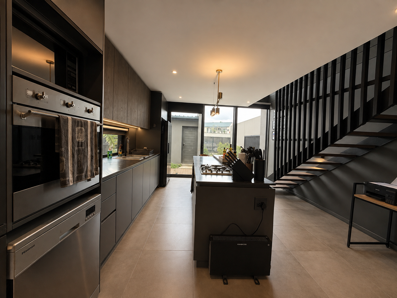 Modern kitchen featuring dark cabinetry, integrated appliances, a central island with gas cooktop, and an adjacent staircase with a sleek metal balustrade.