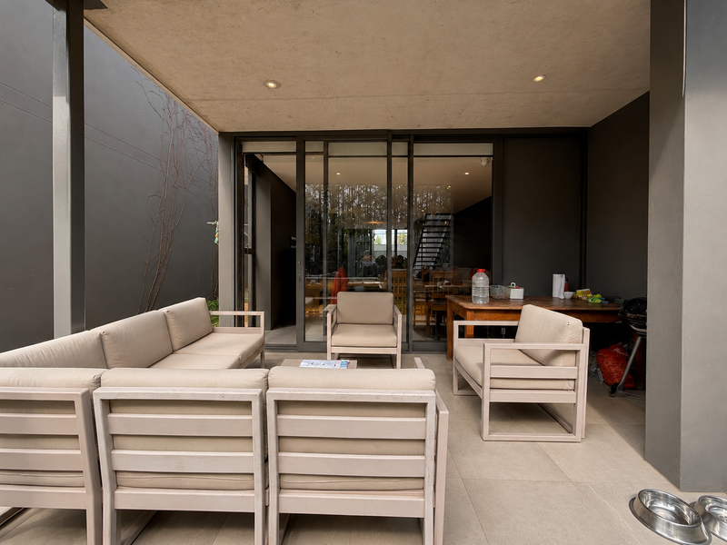 A covered outdoor patio area featuring tiled flooring, recessed lighting, and large sliding glass doors providing seamless access to the interior living space.