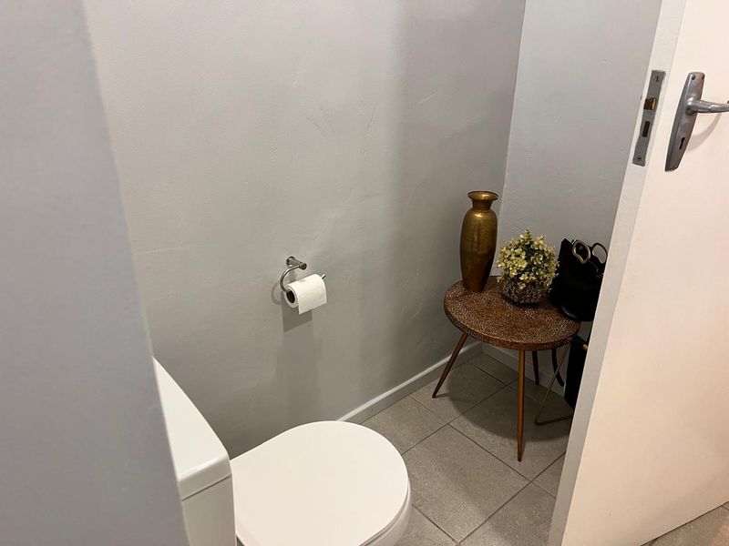 A compact guest bathroom featuring a modern toilet, neutral wall paint, and tiled flooring.