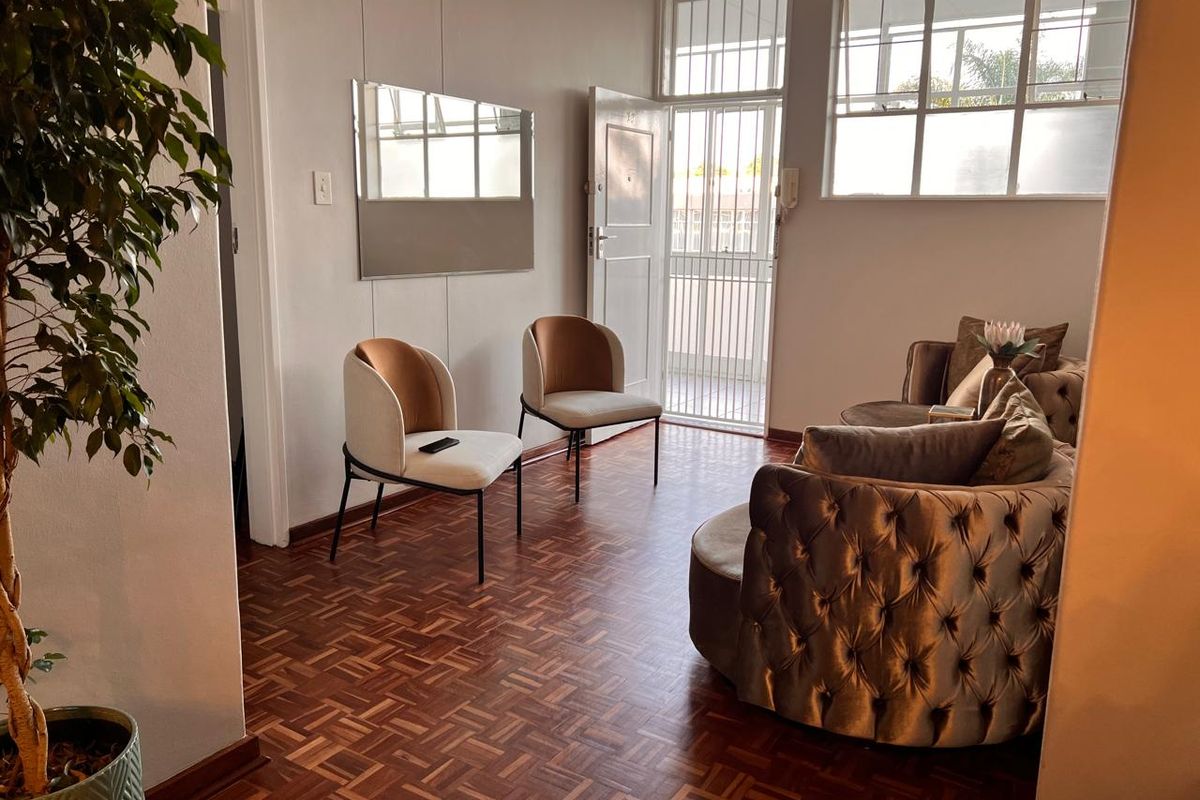 A bright living area featuring classic parquet flooring, a secure entrance gate, and an intercom system, offering a warm and inviting atmosphere.