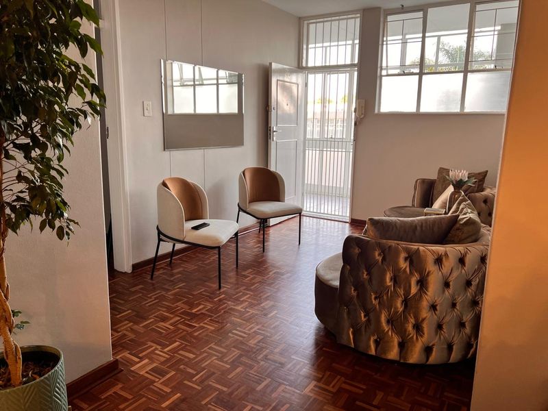 A bright living area featuring classic parquet flooring, a secure entrance gate, and an intercom system, offering a warm and inviting atmosphere.