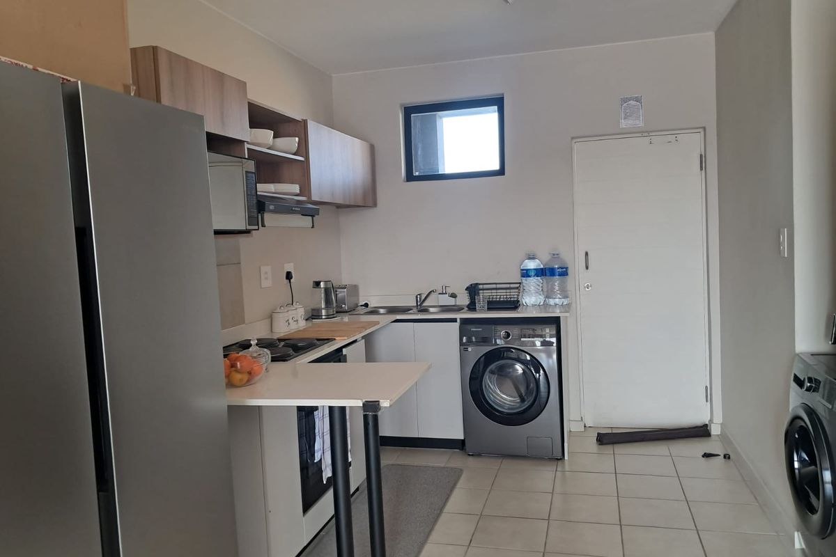 Functional kitchen featuring built-in cabinetry, integrated appliances, tiled flooring, and a dedicated laundry area with washing machine connection.