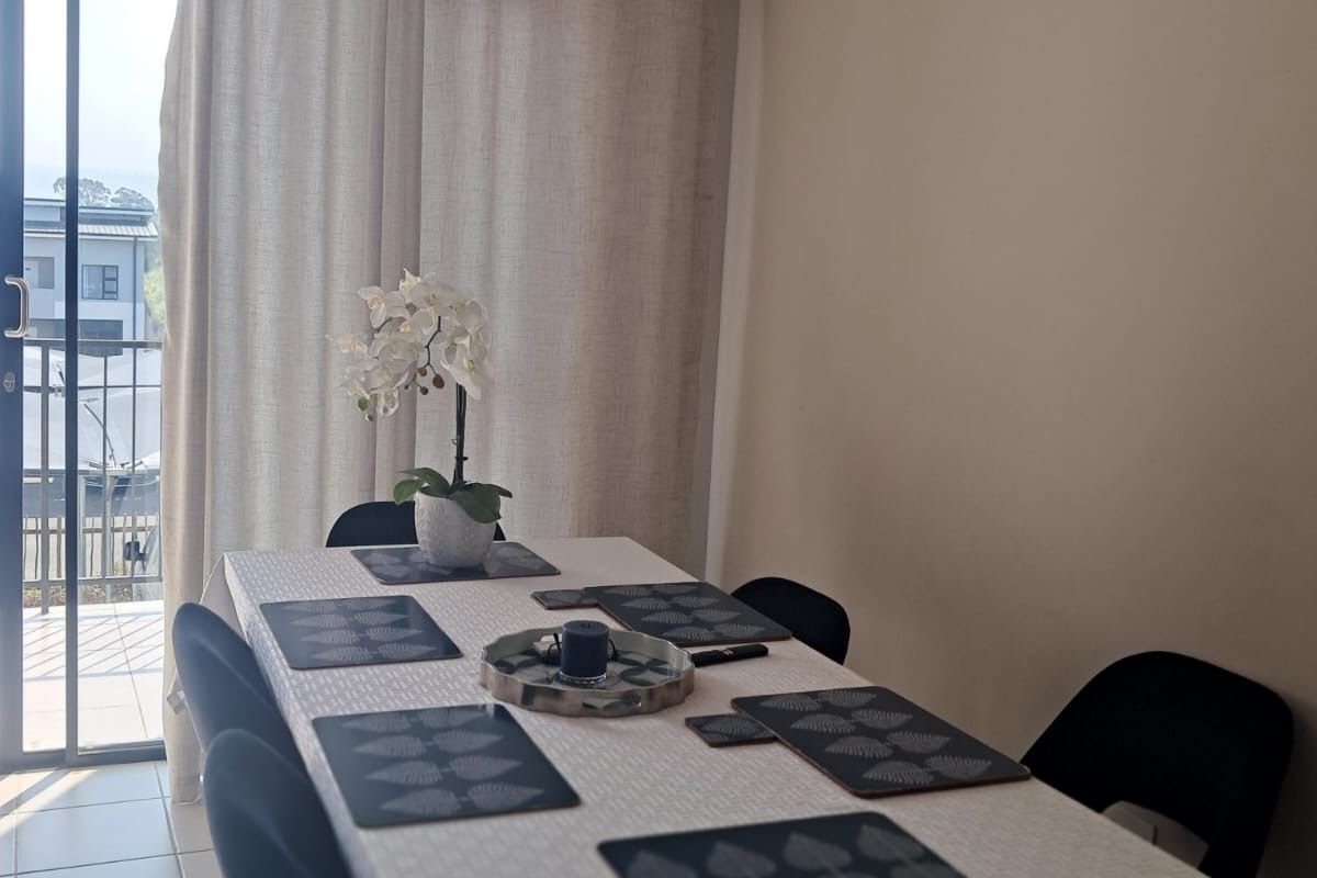 A bright dining area featuring tiled flooring and a sliding glass door providing access to an outdoor balcony space.