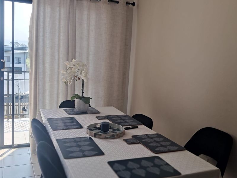 A bright dining area featuring tiled flooring and a sliding glass door providing access to an outdoor balcony space.