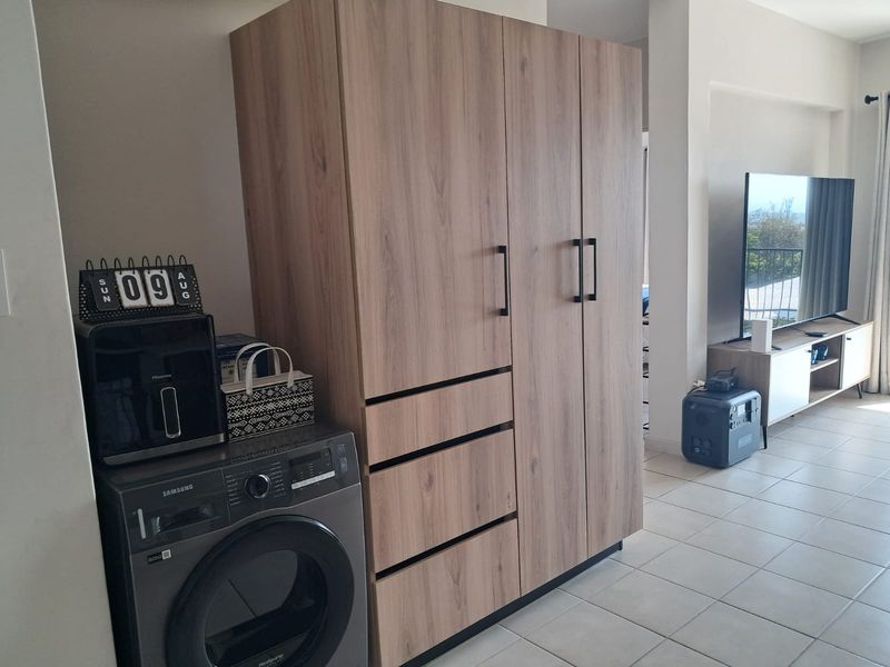 Open plan living area featuring modern wood-finish built-in cabinetry with integrated laundry space and tiled flooring throughout.