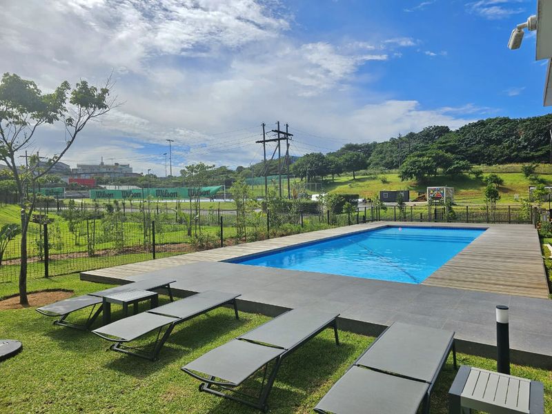 A well-maintained outdoor swimming pool area featuring timber decking, tiled surrounds, and landscaped garden views, perfect for relaxation and recreation.