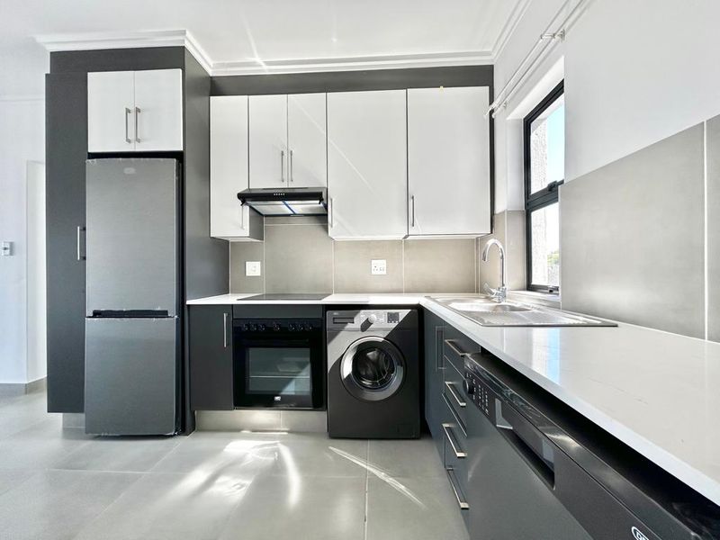Modern kitchen featuring sleek two-tone cabinetry, quartz countertops, integrated appliances, and high-quality tiled finishes in a clean, contemporary layout.