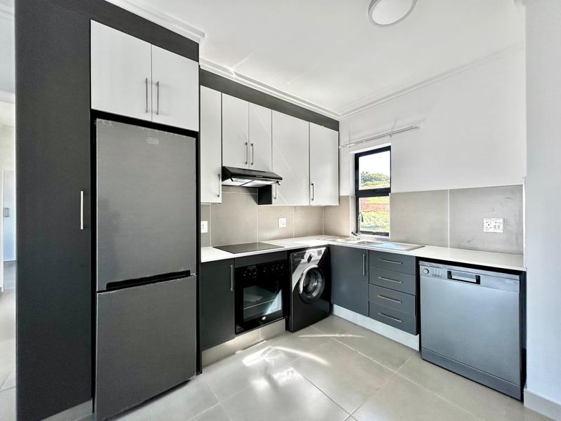 Modern kitchen featuring sleek two-tone cabinetry, integrated appliances, tiled splashbacks, and high-quality finishes throughout.