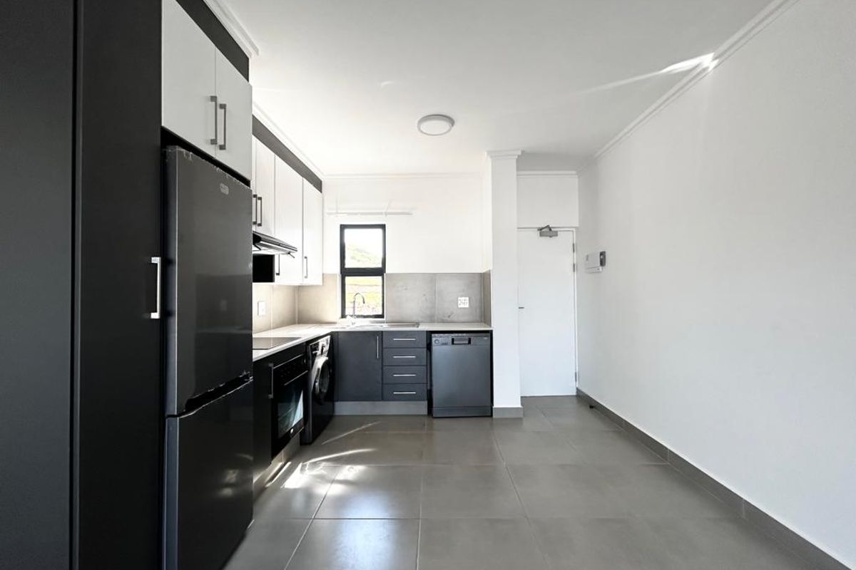 Modern kitchen featuring sleek two-tone cabinetry, integrated appliances, tiled flooring, and a functional layout with ample space for dining.