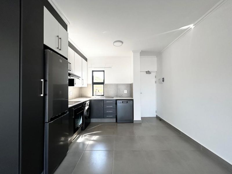 Modern kitchen featuring sleek two-tone cabinetry, integrated appliances, tiled flooring, and a functional layout with ample space for dining.
