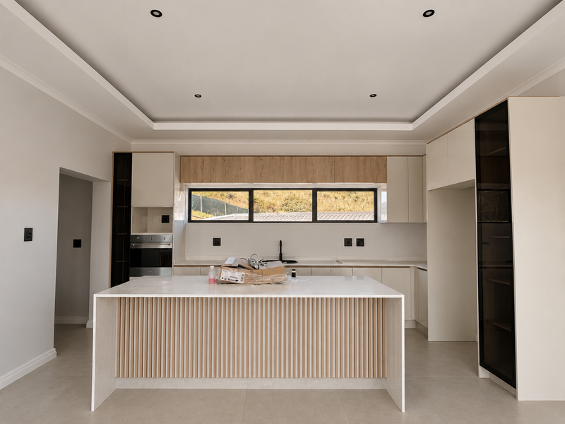 Modern kitchen featuring a central island with fluted detailing, stone countertops, built-in oven, and sleek cabinetry with recessed lighting.