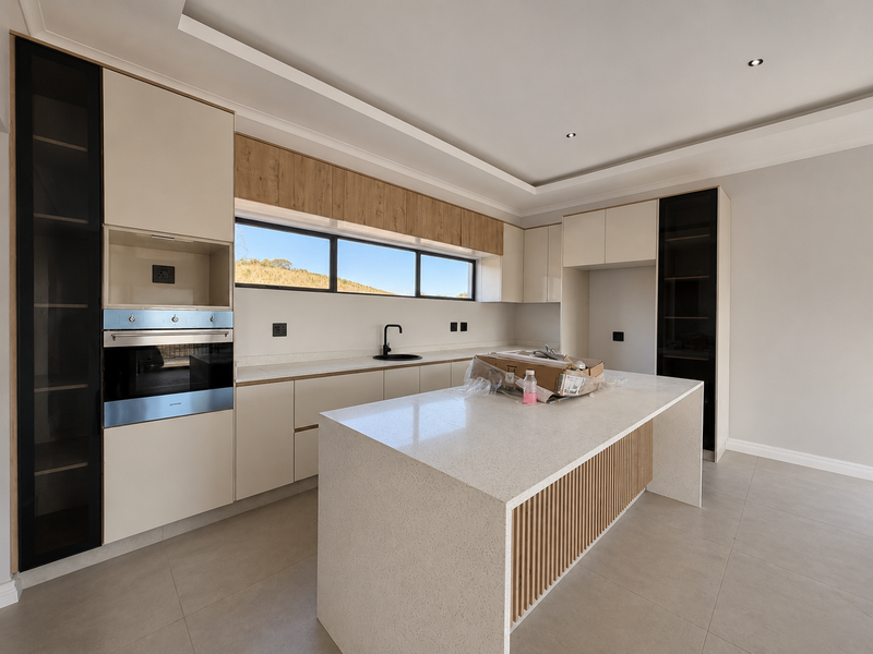 Modern kitchen featuring a central island with quartz countertops, built-in oven, sleek cabinetry, and large windows providing natural light.