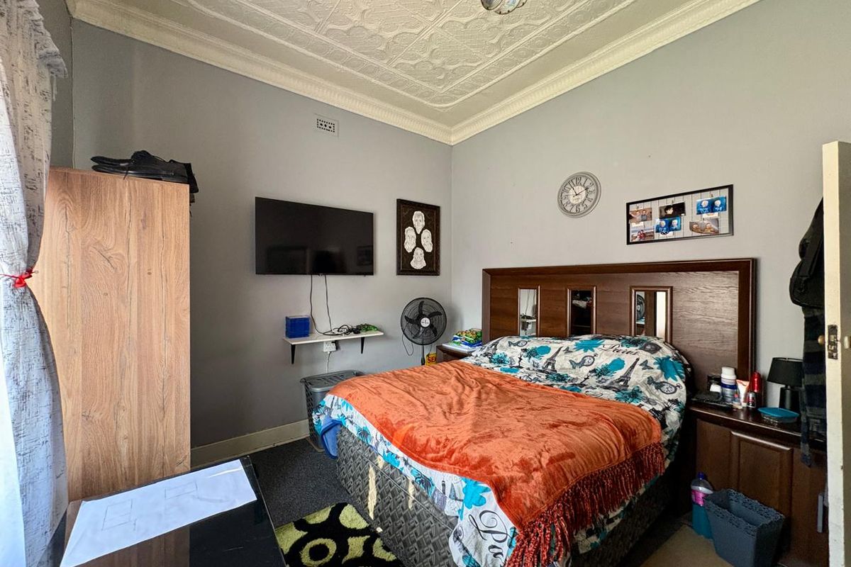 A bedroom featuring high ceilings with ornate period-style decorative cornicing and a ceiling rose.
