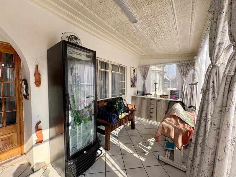 Enclosed patio area featuring classic pressed metal ceilings, tiled flooring, and large windows providing ample natural light.