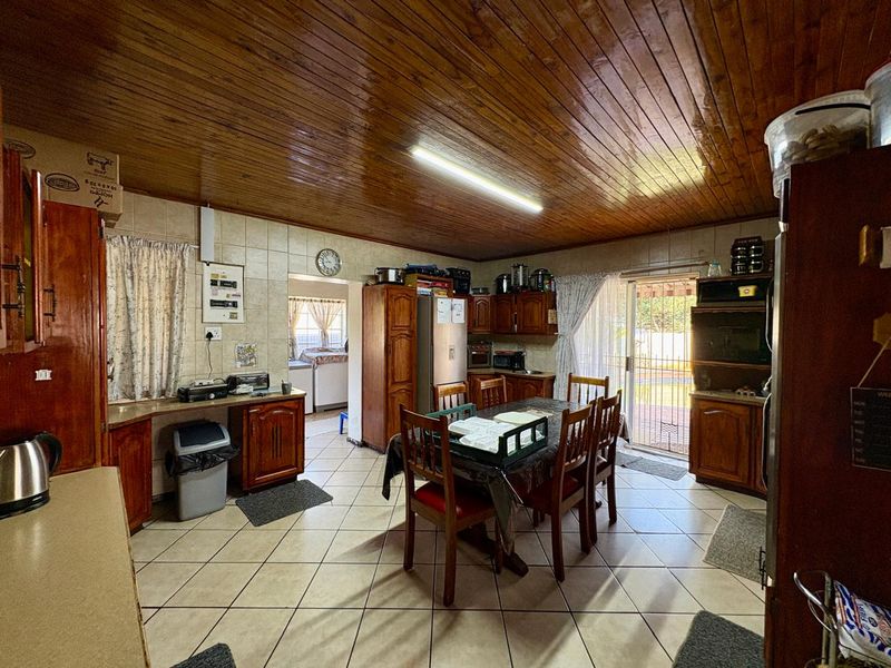 Open plan kitchen and dining area featuring wooden cabinetry, tiled flooring, and a distinctive wooden tongue and groove ceiling with direct access to the patio.