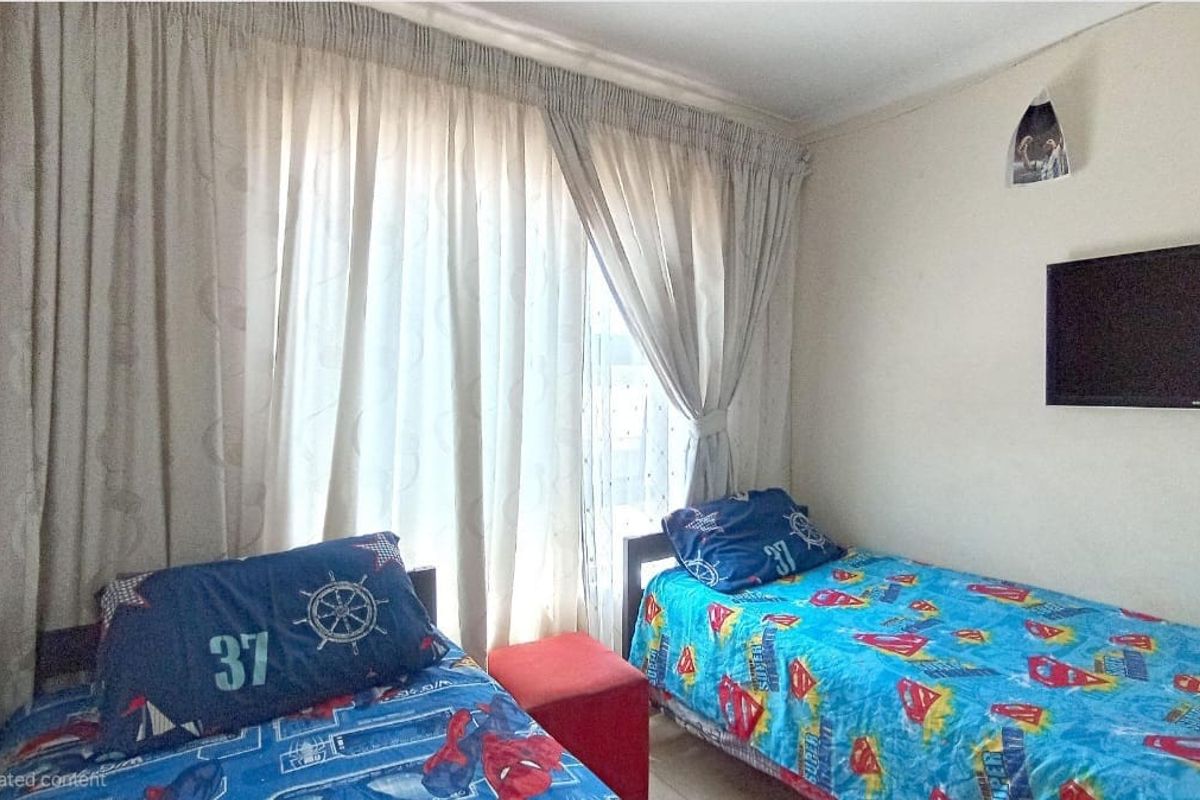 A bedroom featuring a wall-mounted television and large window with curtain tracks.