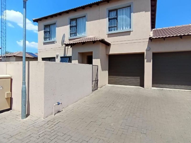 Front elevation of a double-storey townhouse featuring a paved driveway, double garage, and neutral exterior facade.