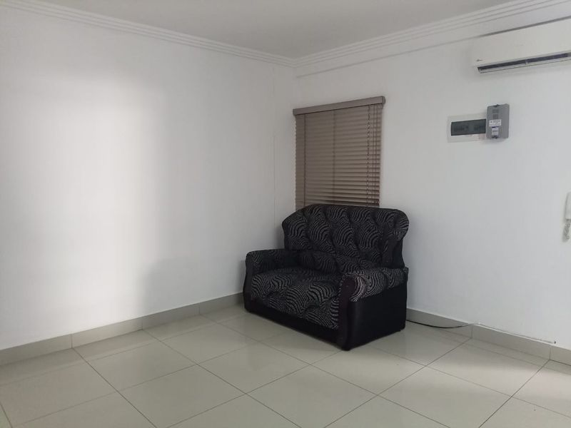 A living area featuring tiled flooring, an installed air conditioning unit, and a wall-mounted electrical distribution board.